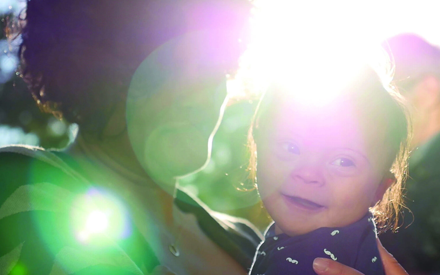 Mother holding her son with Down syndrome as he smiles.